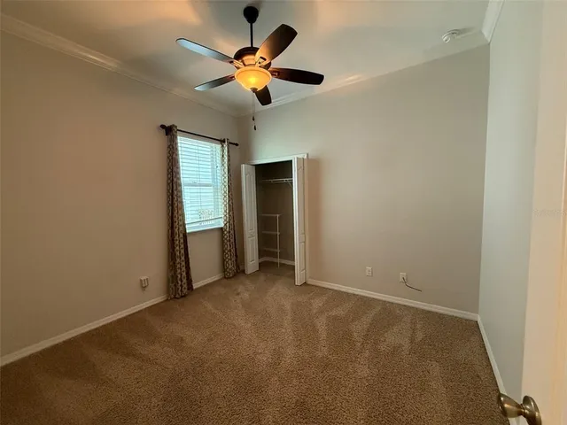 an empty room with a ceiling fan and carpet