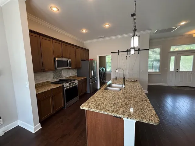 a kitchen with kitchen island granite countertop stainless steel appliances and wooden cabinets