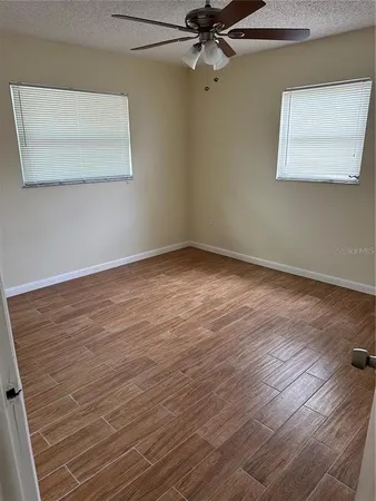 an empty room with wooden floor closet and fan