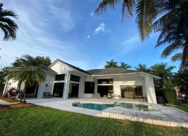 a view of a house with a yard and palm trees