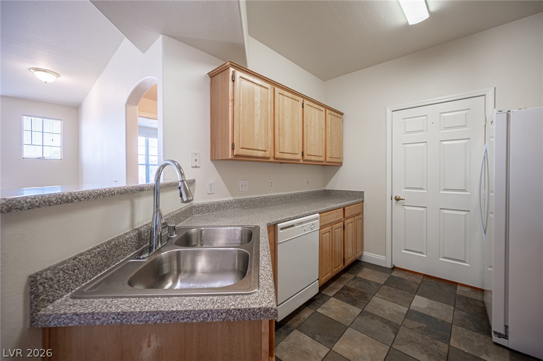 8555 West Russell Road, Unit 2062 Las Vegas, NV 89113 - Photo 15 of 35 A functional kitchen features ample counter space, wood cabinetry, and checkerboard flooring, ideal for everyday meal preparation.