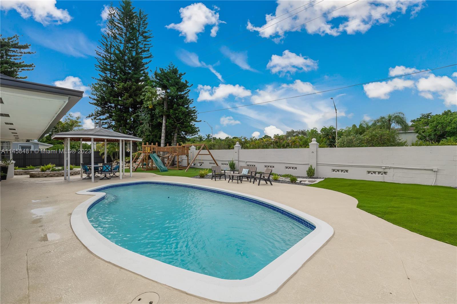 10520 Southwest 103rd Avenue Miami, FL 33176 - Photo 35 of 51 a view of a swimming pool with lawn chairs under an umbrella