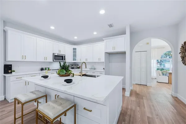 a kitchen with a sink a stove a refrigerator and white cabinets with wooden floor