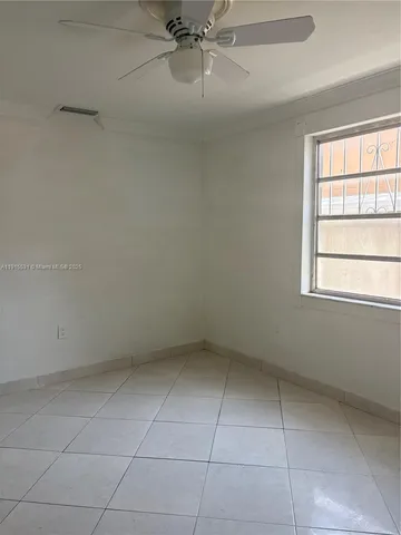 an empty room with a ceiling fan and window