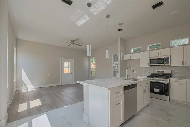 an empty room with wooden floor chandelier fan and windows
