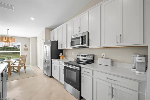 a kitchen with stainless steel appliances granite countertop a stove a sink a refrigerator and white cabinets