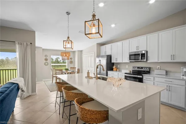 a kitchen with stainless steel appliances granite countertop a stove a sink a microwave a refrigerator a dining table and chairs with wooden floor