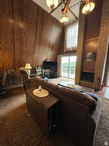 1085 West Elk Road Helper, UT 84526 - Photo 18 of 40 Spacious A-frame interior featuring wood-finish paneling, a prominent brick fireplace, and sliding glass doors