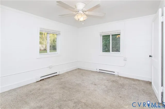 an empty room with chandelier fan and windows
