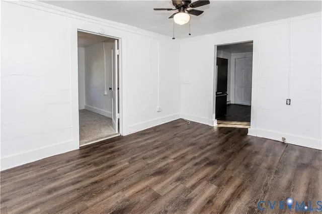 an empty room with wooden floor and a ceiling fan