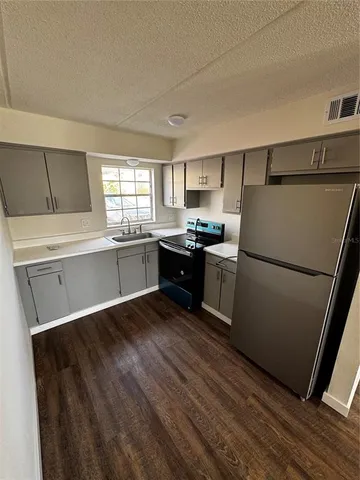 a kitchen with granite countertop a refrigerator sink and cabinets