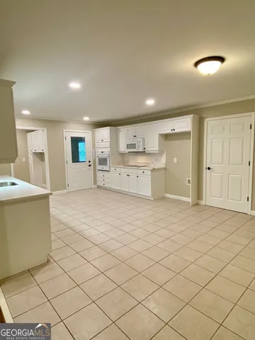 a large white room with a large window and kitchen view