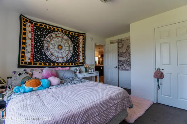 a bedroom with filled bed and a painting on the wall