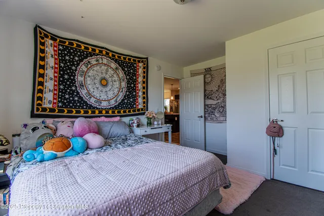 a bedroom with filled bed and a painting on the wall