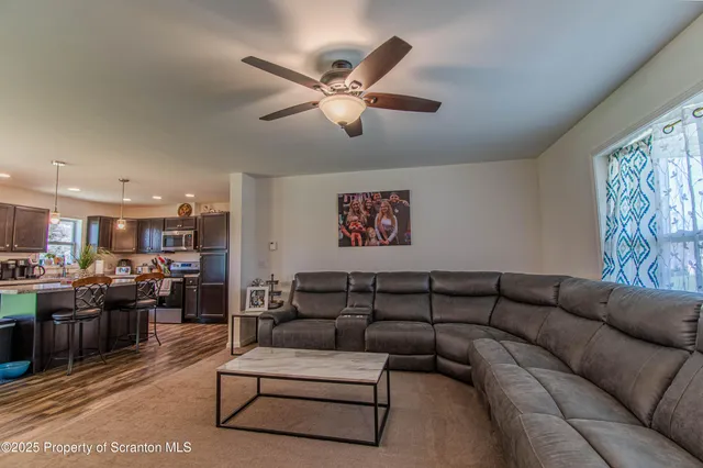 a living room with furniture kitchen view and a chandelier
