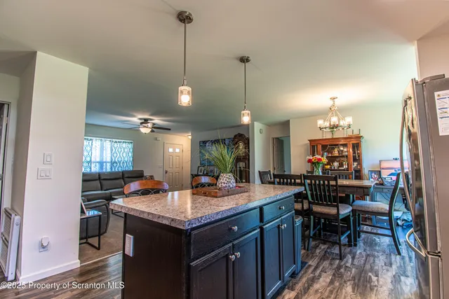 a kitchen with a refrigerator a sink dishwasher a dining table and chairs with wooden floor