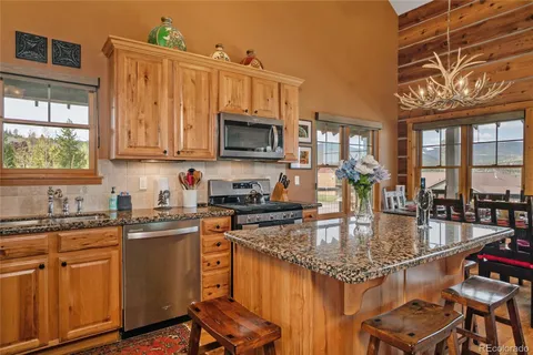 a kitchen with kitchen island granite countertop a stove top oven a sink a counter space and cabinets