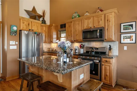 a kitchen with kitchen island granite countertop a stove top oven microwave and refrigerator