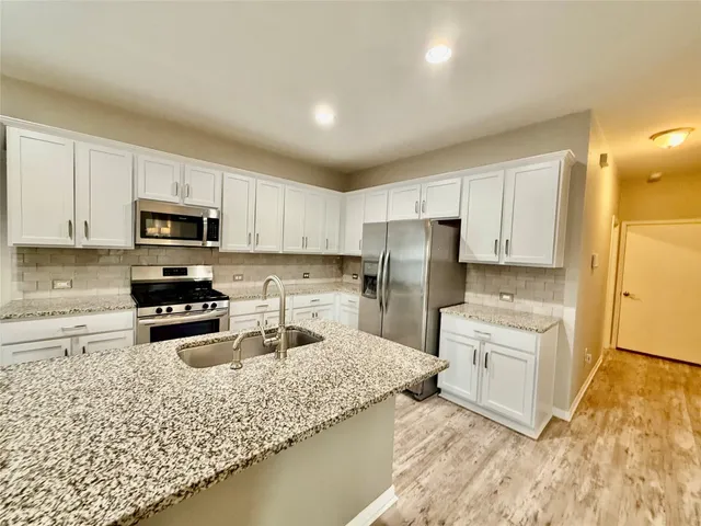 a kitchen with granite countertop a sink stove and microwave