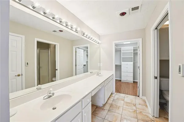 a spacious bathroom with a double vanity sink a mirror and a shower