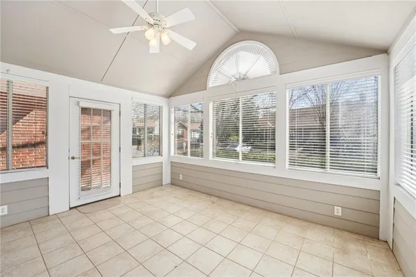 a view of an empty room with a window and chandelier fan