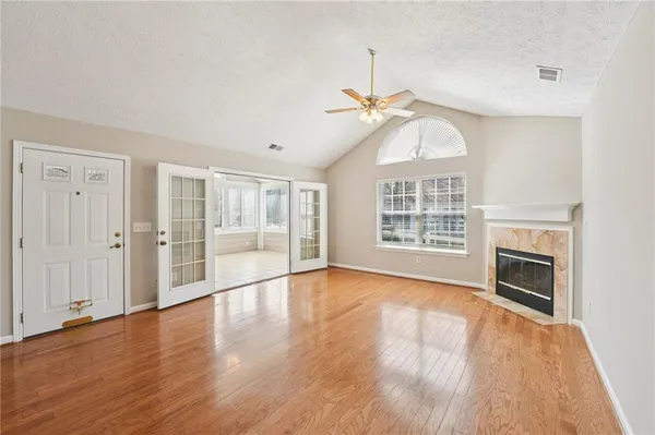 a view of an empty room with wooden floor and a window