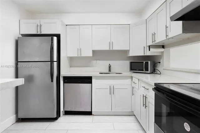 a kitchen with white cabinets and appliances