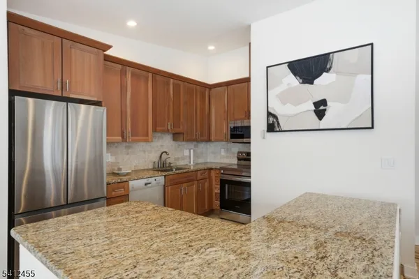 a kitchen with stainless steel appliances granite countertop a stove a refrigerator and a microwave