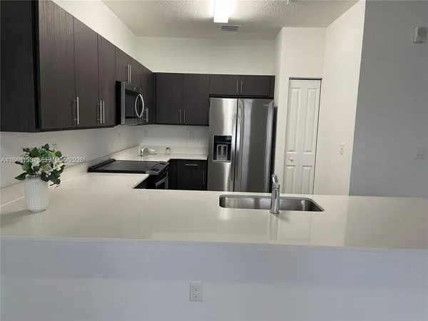 a kitchen with stainless steel appliances a refrigerator a sink a stove and white cabinets