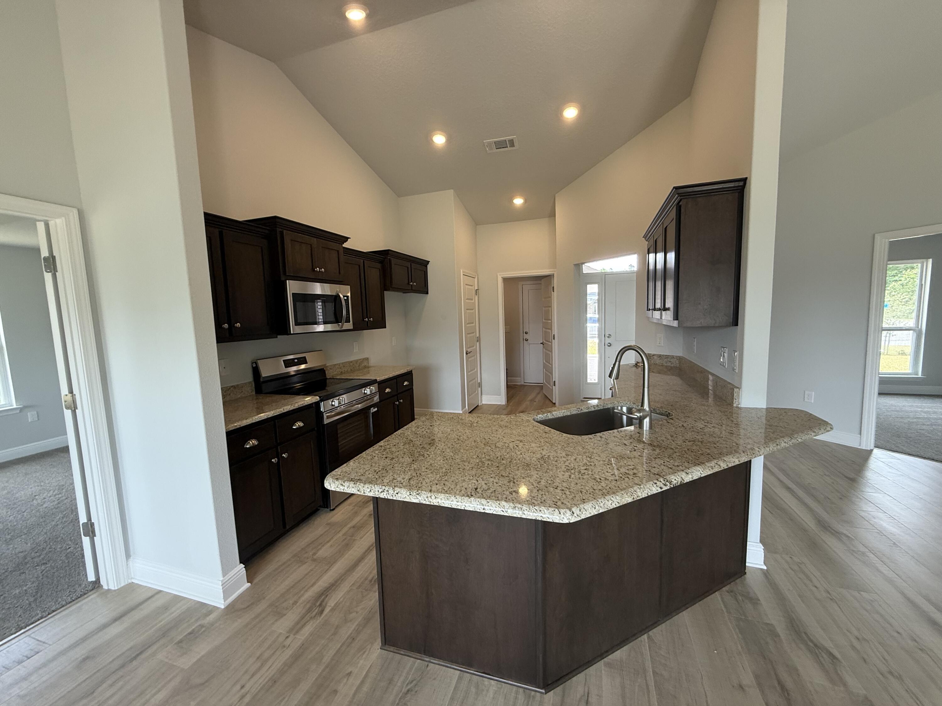 6000 Crocket Cove Crestview, FL 32539 - Photo 13 of 20 a kitchen with kitchen island granite countertop a sink a stove and refrigerator