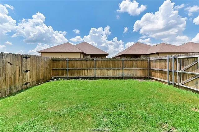 a view of a yard with wooden fence