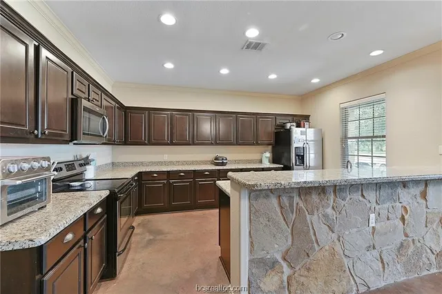 a kitchen with stainless steel appliances granite countertop a stove a sink a microwave oven and a refrigerator
