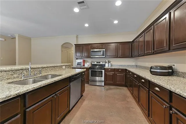 a kitchen with stainless steel appliances granite countertop wooden cabinets a sink and a stove