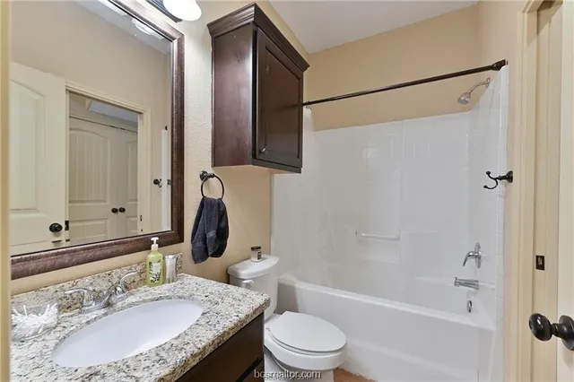a bathroom with a granite countertop sink toilet and shower