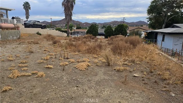 a view of a dry yard with wooden fence