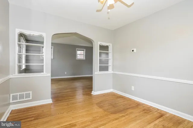 an empty room with wooden floor cabinet and windows