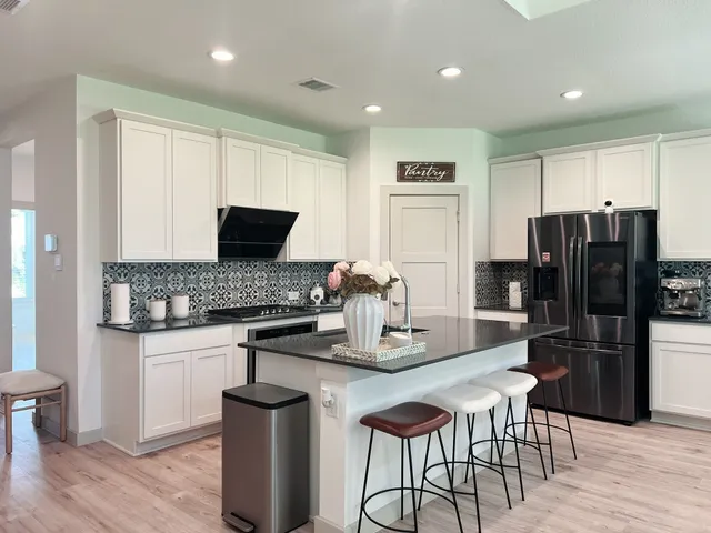 a kitchen with stainless steel appliances granite countertop a refrigerator and a stove top oven