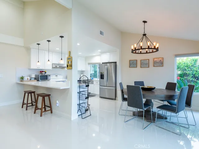 a dining room with furniture a chandelier and kitchen view