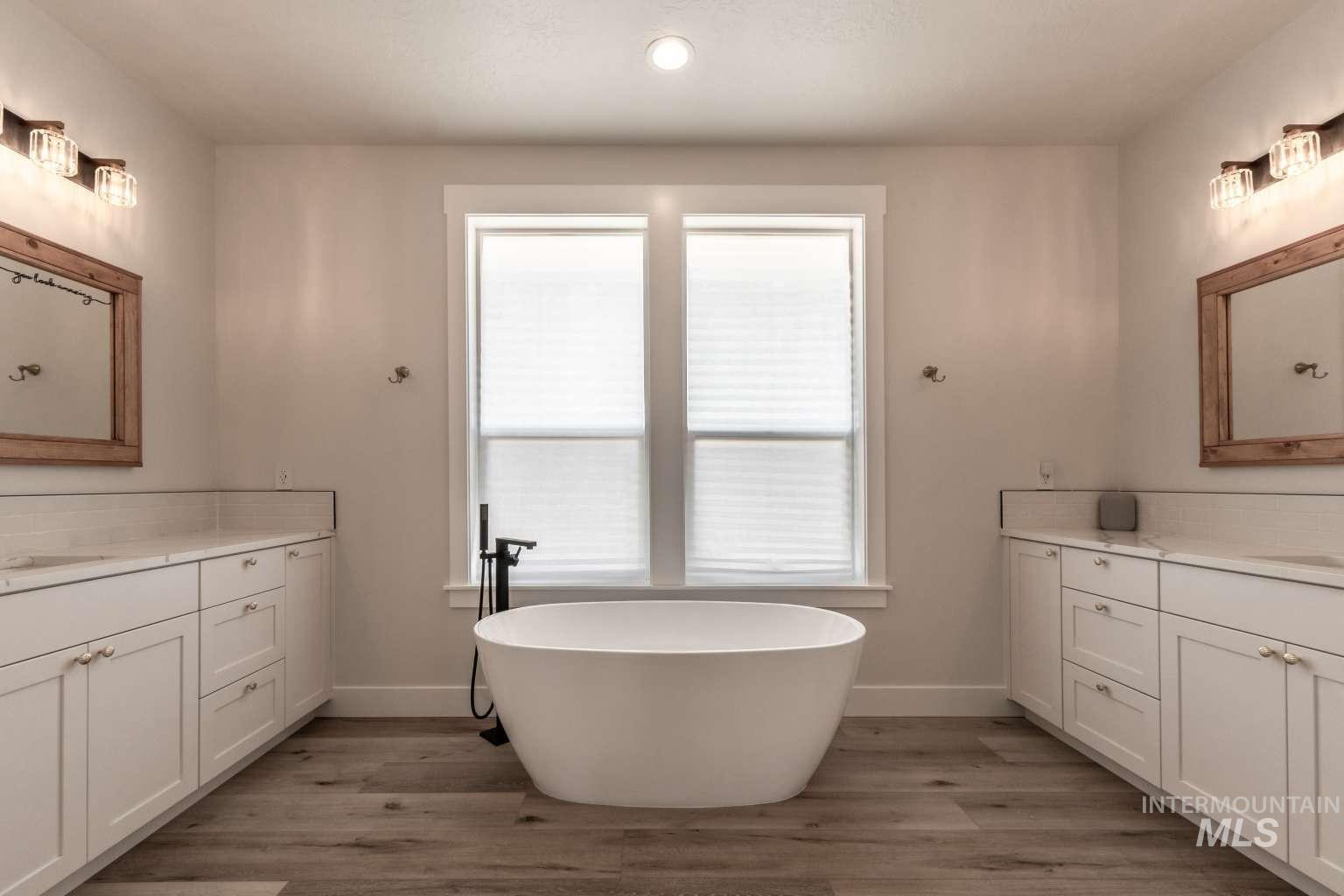 9853 Salmon Ridge Place Nampa, ID 83686 - Photo 13 of 48 Bathroom featuring two vanities, light wood finished floors, backsplash, a freestanding bath, and recessed lighting