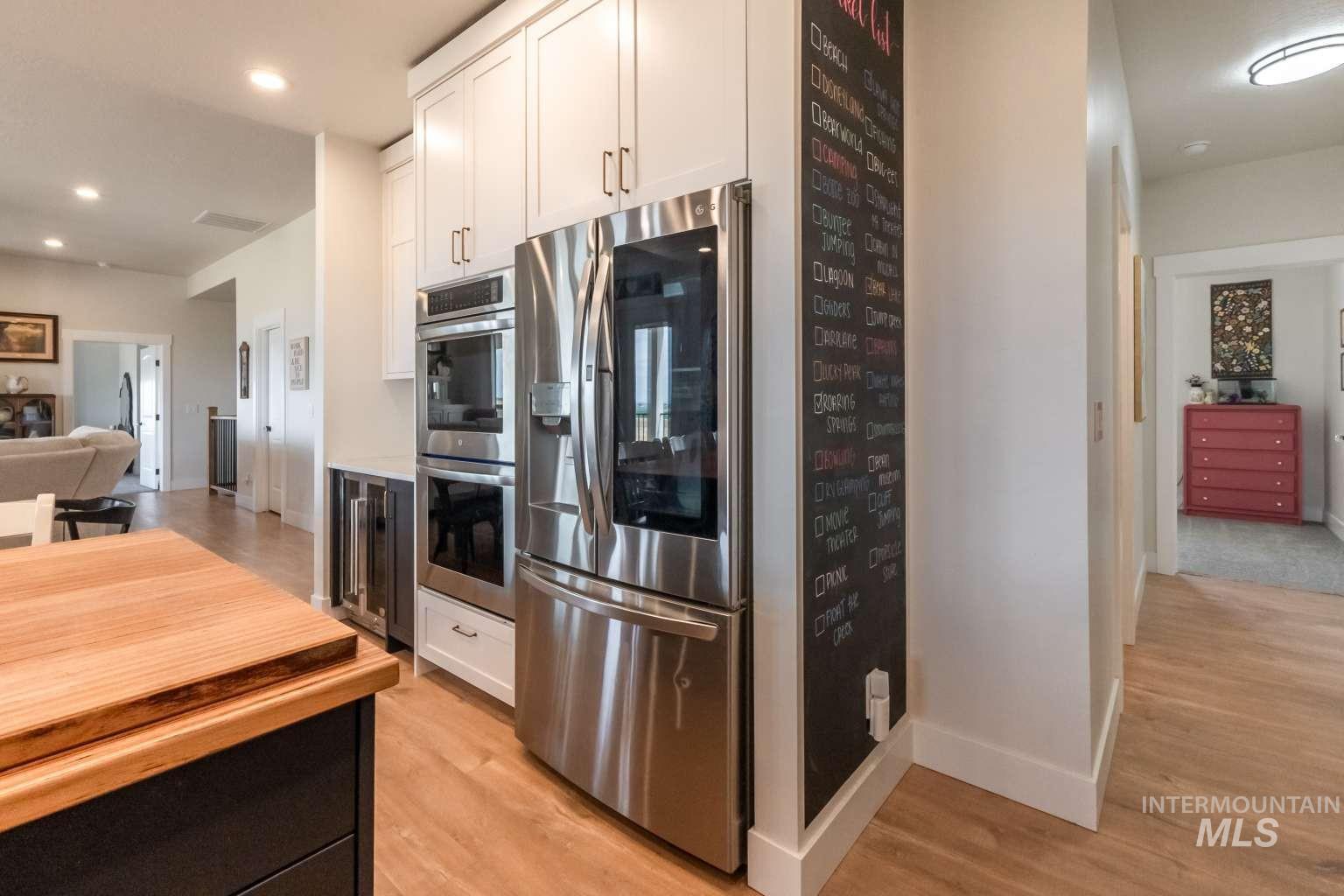 9853 Salmon Ridge Place Nampa, ID 83686 - Photo 19 of 48 Kitchen with stainless steel appliances, wine cooler, two tone cabinets, light wood finished floors, and recessed lighting