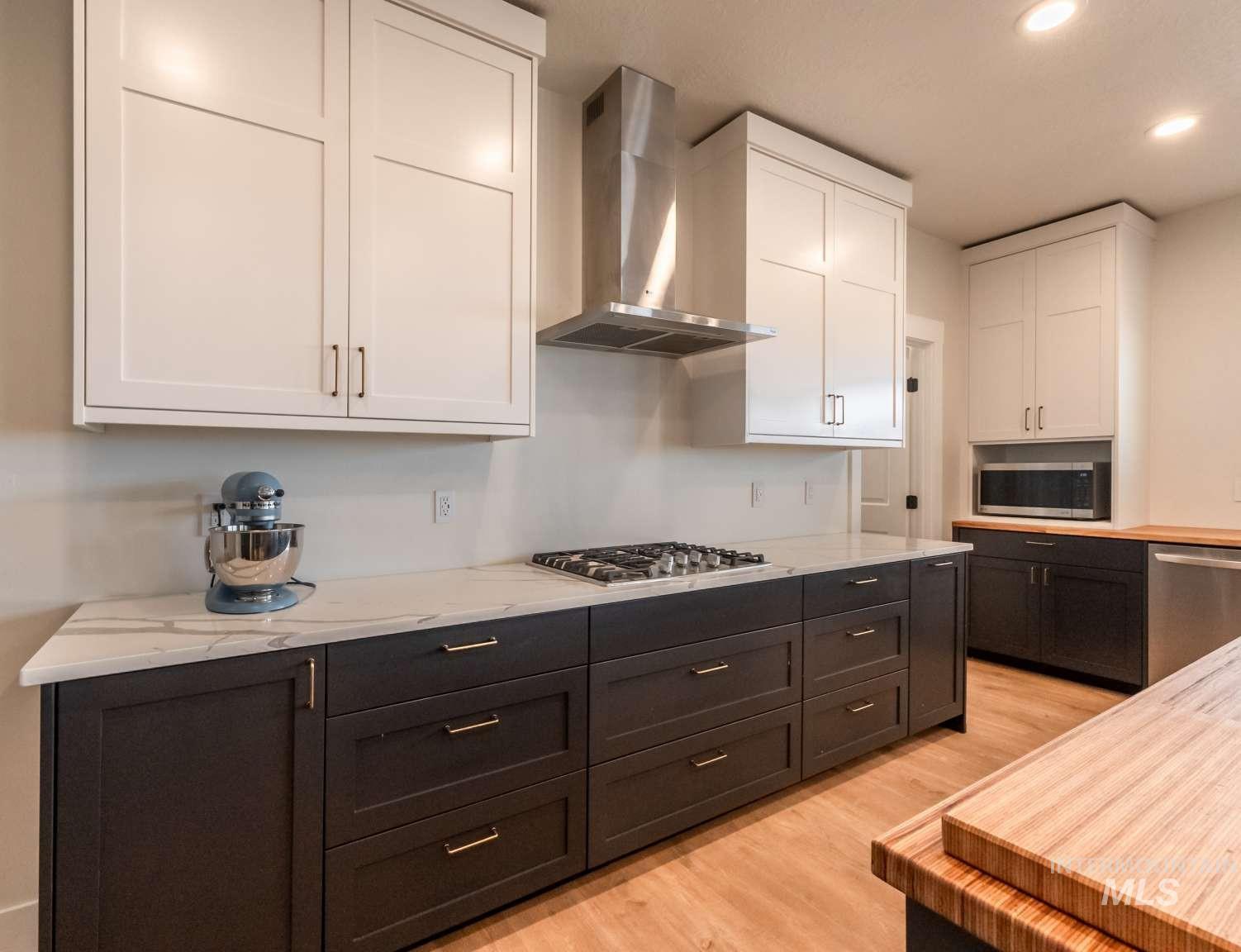 9853 Salmon Ridge Place Nampa, ID 83686 - Photo 26 of 48 Dual tone kitchen featuring dual tone cabinets, light wood-type flooring, recessed lighting, stainless steel appliances, and light stone countertops
