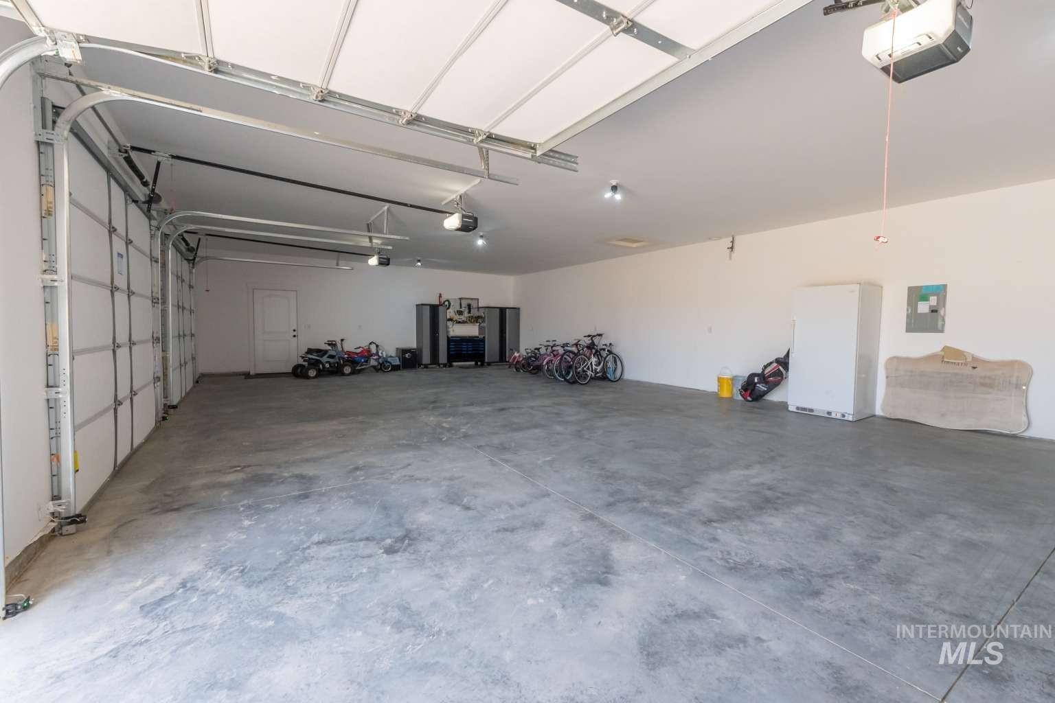 9853 Salmon Ridge Place Nampa, ID 83686 - Photo 36 of 48 Garage with freestanding refrigerator, a garage door opener, and electric panel