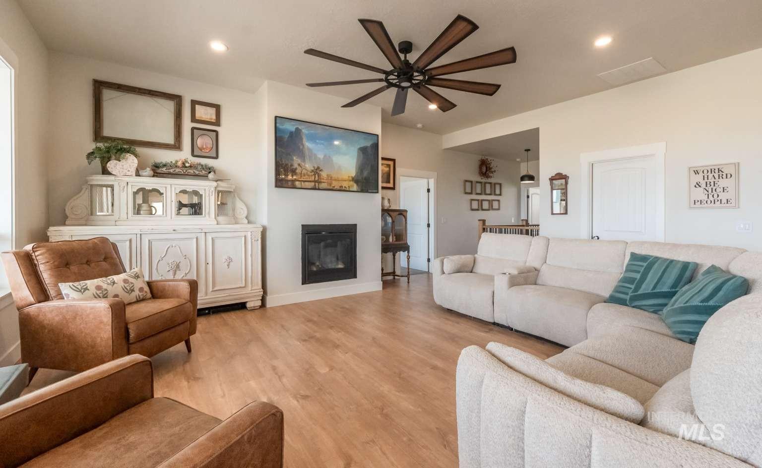 9853 Salmon Ridge Place Nampa, ID 83686 - Photo 7 of 48 Living area with light wood finished floors, a glass covered fireplace, a ceiling fan, and recessed lighting