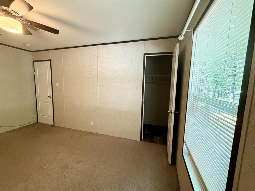 145 Adalida Lane Springtown, TX 76082 - Photo 22 of 29 Carpeted room featuring a ceiling fan with integrated lighting, a panel door, and a window with blinds