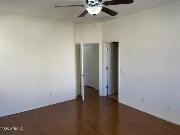 an empty room with wooden floor fan and windows