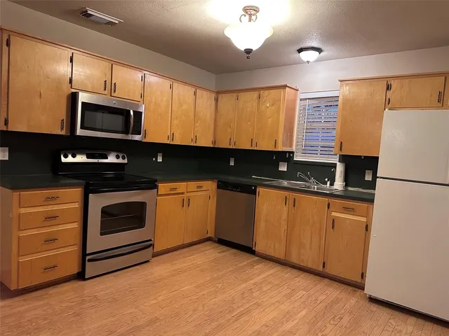 a kitchen with granite countertop a refrigerator stove top oven a sink and dishwasher