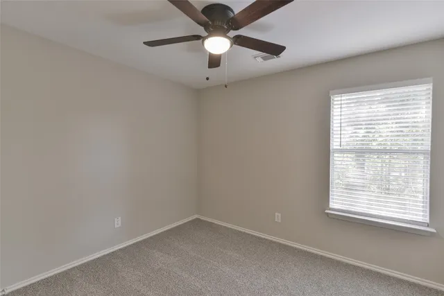 an empty room with a window and a fan