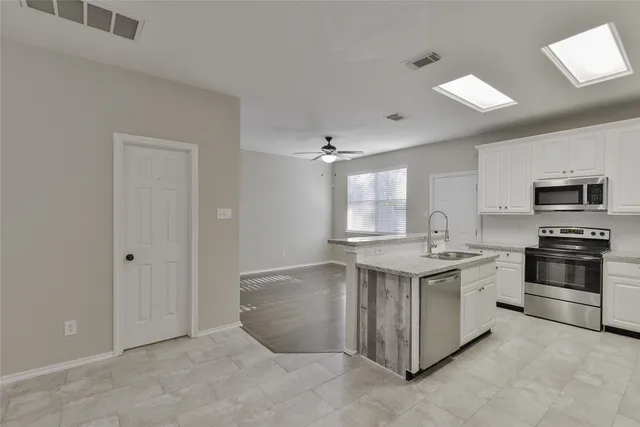 a view of a kitchen with a sink and dishwasher a stove top oven with wooden floor