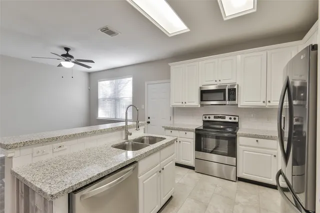 a kitchen with stainless steel appliances granite countertop a sink stove microwave and refrigerator
