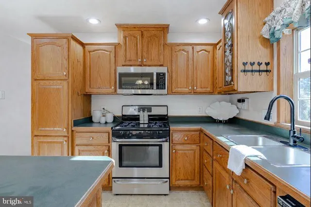 a kitchen with stainless steel appliances a stove a sink a microwave a refrigerator and cabinets